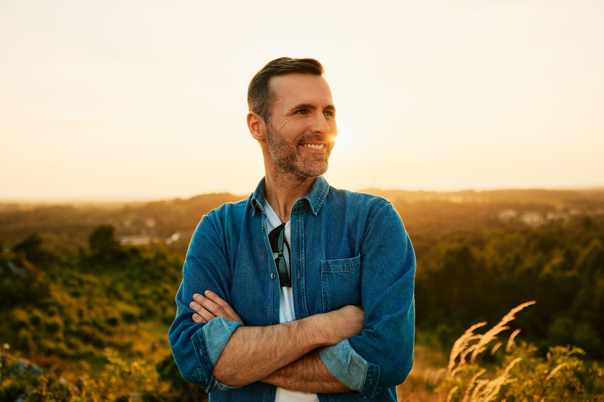 Portrait of smiling man standing outdoors while hiking during sunny weekend in nature